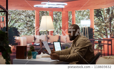 Startup entrepreneur calculating the annual sales reports to review the budget, working to develop the business activity. Businessman analyzing profit and expenses on his laptop at home. Camera B. Startup entrepreneur calculating the annual sales reports to review the budget, working to develop the business activity. Businessman analyzing profit and expenses on his laptop at home. Camera B. 118603632