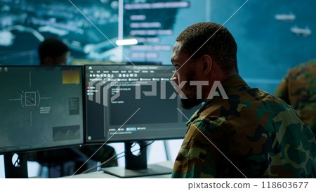 Soldier working with AI intelligence on pc in control room, processing live data on cctv systems. Surveillance efforts to support field missions and defense operations, national security. Camera A. Soldier working with AI intelligence on pc in control room, processing live data on cctv systems. Surveillance efforts to support field missions and defense operations, national security. Camera A. 118603677