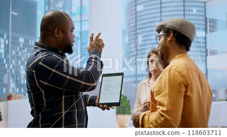 Real estate investment expert and entrepreneur planning an office space relocation, examining blueprints and discussing the layout for the new workspace. Looking to buy urban property. Camera A. 118603711