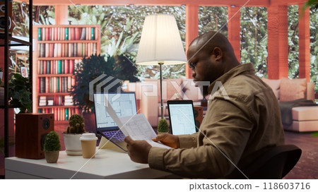 Businessman evaluating architectural blueprints for a modern office space, using strategic planning new commercial workspace leasing for his startup. Hunting for real estate property. Camera B. Businessman evaluating architectural blueprints for a modern office space, using strategic planning new commercial workspace leasing for his startup. Hunting for real estate property. Camera B. 118603716