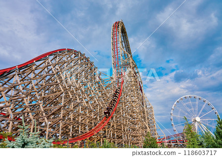 People riding at roller coaster attraction in amusement park. Entertainment at summer holiday 118603717