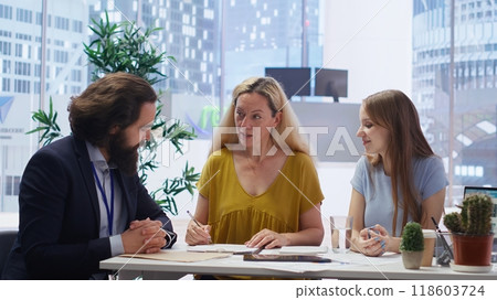 Customers completing paperwork, taking loan from economic agent, finishing lucrative deal. Parent and gen Z girl signing contract, entering agreement with financial consultant, camera B Customers completing paperwork, taking loan from economic agent, finishing lucrative deal. Parent and gen Z girl signing contract, entering agreement with financial consultant, camera B 118603724