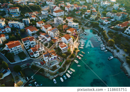 Birds eye view of sea coast with small town along seashore. Aerial top view of coastal village with red-roofed houses and boats near shore. Tourist town Rogoznica in Croatia on Adriatic Sea 118603751
