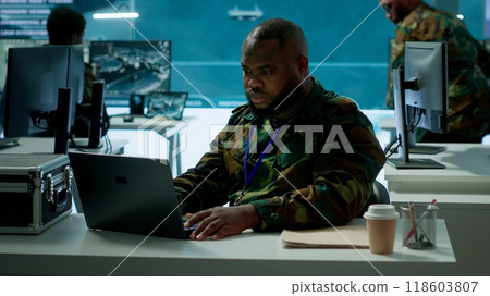 Intelligence agents in modern operations center managing surveillance activity and synchronizing security protocols. Army base staff interpret real time data to protect national interests. Camera A. 118603807