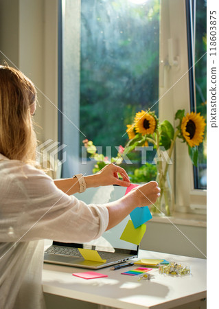 Woman is using sticky notes on her laptop screen to organize her work while working remotely from home. Concept of planning and task management in office work Woman is using sticky notes on her laptop screen to organize her work while working remotely from home. Concept of planning and task management in office work 118603875