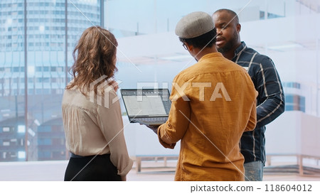 Business development team reviewing architectural plans for a high class office, considering a real estate investment strategy. Managers negotiating with the realtor during an office tour. Camera B. 118604012