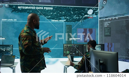 Military team operating in a high tech command post control tower, focusing on surveillance tactics for intelligence gathering. Data protection to manage critical information operations. Camera B. Military team operating in a high tech command post control tower, focusing on surveillance tactics for intelligence gathering. Data protection to manage critical information operations. Camera B. 118604014