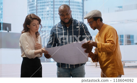 Client discussing with the real estate agent about architectural change and renovation, reviewing blueprints plans during office tour. Entrepreneur negotiating a leasing contract deal. Camera B. Client discussing with the real estate agent about architectural change and renovation, reviewing blueprints plans during office tour. Entrepreneur negotiating a leasing contract deal. Camera B. 118604092