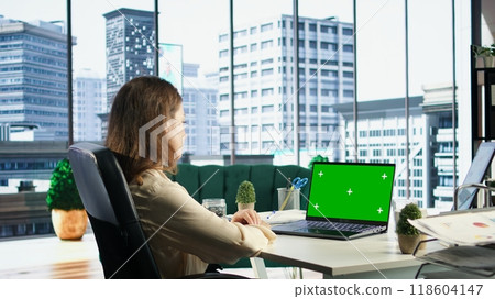 Woman company leader looking at isolated chroma key display in high end urban office, ambitious driven CEO with executive power. Businesswoman with strategic thinking in corporation. Camera A. 118604147