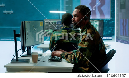 Soldiers in a state of the art military control room collaborate on data analysis, intelligence gathering, and mission planning. Ensure effectiveness and security of military operations. Camera A. 118604167