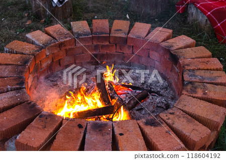 A round brick fire pit with burning wood 118604192