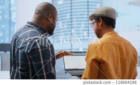 Corporate clients evaluating an investment opportunity in real estate, reviewing architectural blueprints and discussing the best strategies for office relocation and creative development. Camera B. 118604286