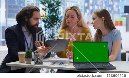 Financial advisor presenting financial guide to customers using green screen laptop. Agent in office assisting clients with investment portfolio management helped by chroma key notebook, camera B 118604316