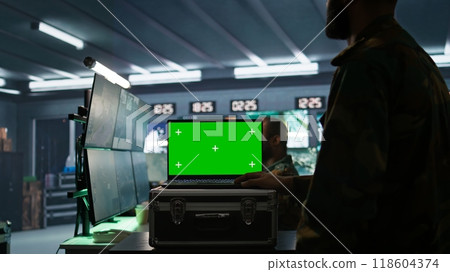 Soldier using tracking software on green screen laptop to gain info against enemies. Army expert using chroma key notebook to gain intel helping troops, coordinating mission activities, camera B Soldier using tracking software on green screen laptop to gain info against enemies. Army expert using chroma key notebook to gain intel helping troops, coordinating mission activities, camera B 118604374