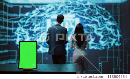 Engineers use green screen tablet and AI neural networks modeled after human brain to solve complex problems. Workers using artificial intelligence and mockup device to look at company data, camera B Engineers use green screen tablet and AI neural networks modeled after human brain to solve complex problems. Workers using artificial intelligence and mockup device to look at company data, camera B 118604384