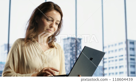 Female CEO leader working on financial planning and budget allocation, ensuring the company resources are used effectively to achieve maximum profit and long term objectives in office. Camera B. Female CEO leader working on financial planning and budget allocation, ensuring the company resources are used effectively to achieve maximum profit and long term objectives in office. Camera B. 118604439