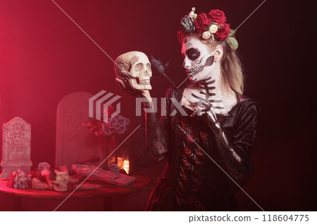 Woman doing Hamlet scene at Day of the Dead event to remember the deceased. Lady posing with skull in hand at theatre play for Mexican holiday of remembrance for those who have passed 118604775