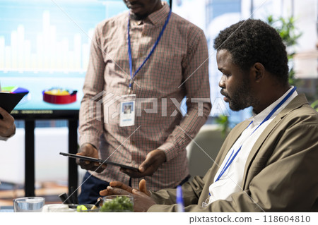 Team of business associates reviewing statistics and infographics on a tablet, working together to gather insight for enterprise development. Employees discussing legal changes at a meeting. 118604810
