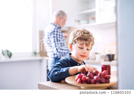 Boy and grandpa making breakfast in the kitchen. Grandfather spending time with grandson, taking care of him while parents are at work. 118605103