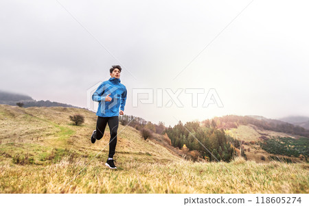 Male runner jogging in nature on dirt running trail. Morning running training for young man. Male runner jogging in nature on dirt running trail. Morning running training for young man. 118605274