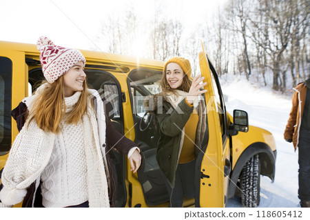 Friends going skiing at ski resort, spending the Christmas holidays together in a cabin. Driving car through a snowy landscape. 118605412