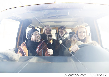Friends traveling by car on winter holiday, spending Christmas in cabin. Driving through snowy landscape. 118605417