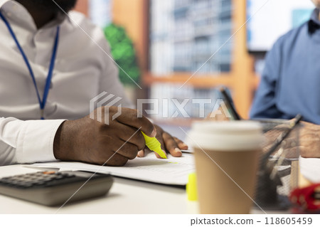 Financial expert highlighting contract terms to explain to old clients in modern office, helping senior people with professional advice. Choosing a retirement plan option. Close up. 118605459