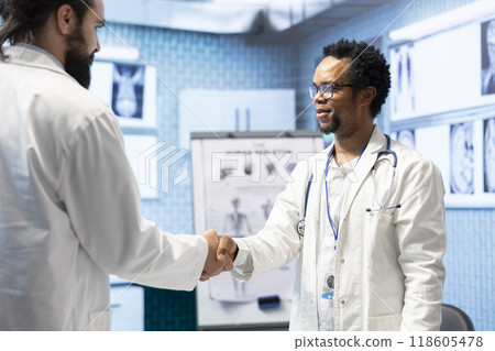 Diverse medics shaking hands after a successful treatment plan collaboration during a meeting with licensed physicians. Doctors with expertise doing a handshake for great partnership in office. 118605478