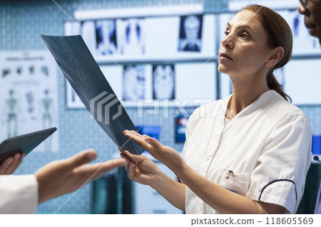 Healthcare team examines x ray results and discusses disease prevention during a meeting with medical staff, treatment options. Radiology experts analyzing scans for diagnostic. Healthcare team examines x ray results and discusses disease prevention during a meeting with medical staff, treatment options. Radiology experts analyzing scans for diagnostic. 118605569