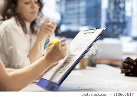 HR employee using highlighter marker on paperwork, ensuring candidate possesses skills needed to fulfil role. HR manager highlighting text on documents, evaluating applicant 118605617