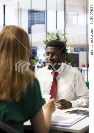 Headhunter tasked with hiring best talent to fill open company position, interviewing man. Employer hired to assess skills and qualifications of african american candidate, doing meeting in office 118605626