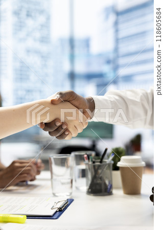 Team leader shaking hands with newly hired employee, welcoming him, close up shot. Businesspeople meeting, doing greeting handshake gesture in office workspace before starting negotiations Team leader shaking hands with newly hired employee, welcoming him, close up shot. Businesspeople meeting, doing greeting handshake gesture in office workspace before starting negotiations 118605684