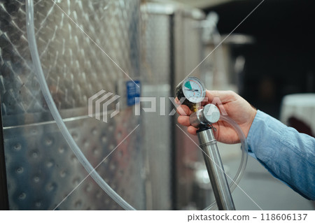 Winemaker standing in the wine cellar, controlling pressure in fermentation tank. Winemaker standing in the wine cellar, controlling pressure in fermentation tank. 118606137