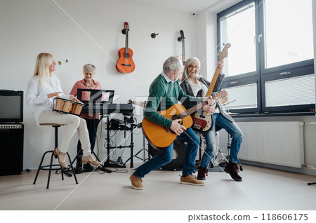 Group of seniors meeting to play musical instruments together in band, having fun. Therapeutic effect of music for elderly people. Group of seniors meeting to play musical instruments together in band, having fun. Therapeutic effect of music for elderly people. 118606175