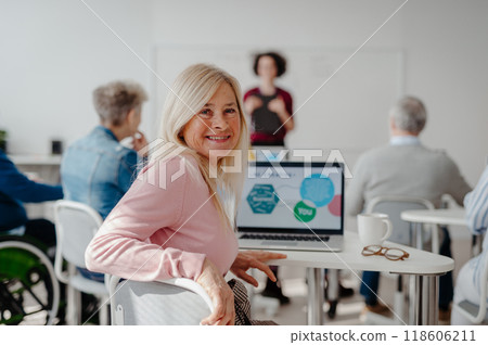 Portrait of female senior student learning how to work with digital technology. Elderly people attending computer and technology education class. Digital literacy. Portrait of female senior student learning how to work with digital technology. Elderly people attending computer and technology education class. Digital literacy. 118606211