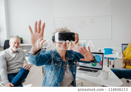 Group of seniors with VR goggles on computer and technology education class. Elderly people learning about virtual reality, using VR headset. Group of seniors with VR goggles on computer and technology education class. Elderly people learning about virtual reality, using VR headset. 118606213