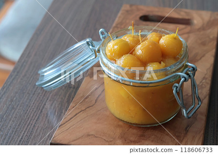 Glass jar of apple jam on wooden olive board. Home made fruit from garden. Kitchen interior and organic food.  118606733