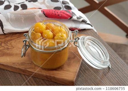 Glass jar of apple jam on wooden olive board. Home made fruit from garden. Kitchen interior and organic food. Glass jar of apple jam on wooden olive board. Home made fruit from garden. Kitchen interior and organic food. 118606735