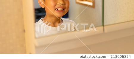 A 10-year-old boy is worried about his missing lower baby teeth (canines) and is checking them in the mirror A 10-year-old boy is worried about his missing lower baby teeth (canines) and is checking them in the mirror 118606834