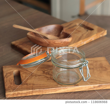 Empty glass jar on olive wood board and heart-shaped wooden jam bowl. Kitchen tools for preparing fruit. Empty glass jar on olive wood board and heart-shaped wooden jam bowl. Kitchen tools for preparing fruit. 118606988