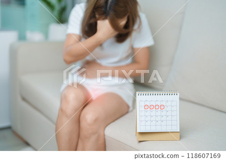Menstruation period cycle of monthly and Stomachache concepts. woman having abdomen pain with calendar, illness female suffer from premenstrual ache and body Health problem on sofa at home 118607169