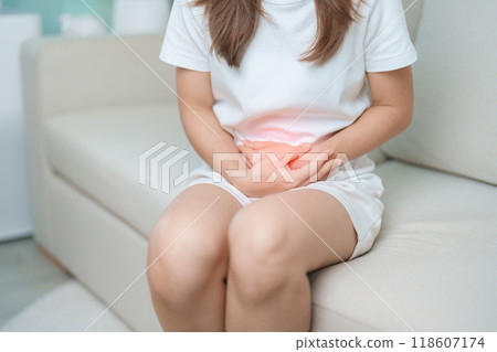 woman having abdomen ache due to Stomach pain, digestion with constipation or Diarrhea from food poisoning, female problem and Endometriosis, Hysterectomy, Stomachache and Menstrual on sofa at home 118607174