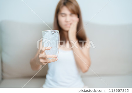 Teeth Sensitive to Cold concept. woman hold Ice Water glass and having toothache and pain after eat. Tooth Decay or Gum Disease, Grinding Teeth and Stress, Exposed Nerve Roots, Crack and Receding Gums Teeth Sensitive to Cold concept. woman hold Ice Water glass and having toothache and pain after eat. Tooth Decay or Gum Disease, Grinding Teeth and Stress, Exposed Nerve Roots, Crack and Receding Gums 118607235