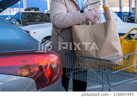 Man Loading Groceries into Car Trunk Man Loading Groceries into Car Trunk 118607445