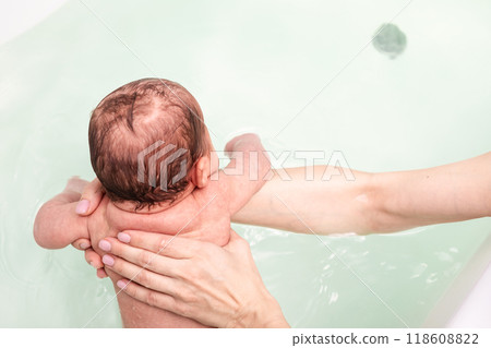Top view of newborn baby held in water during bath time Top view of newborn baby held in water during bath time 118608822