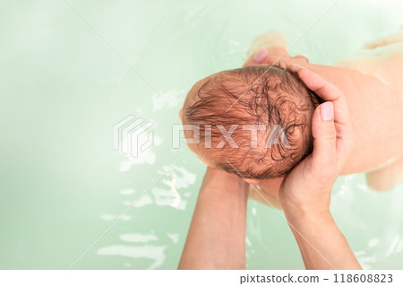 Top view of newborn baby held in water during bath time 118608823
