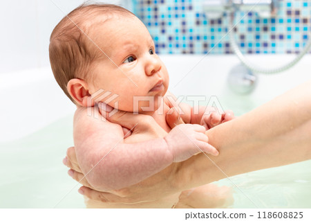 Newborn baby held in a bath during a bath time routine 118608825