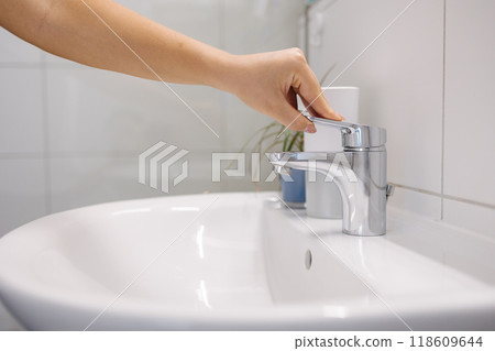 The woman tries to turn on the water in the bathtub, but no water comes out The woman tries to turn on the water in the bathtub, but no water comes out 118609644