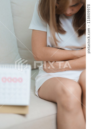 Menstruation period cycle of monthly and Stomachache concepts. woman having abdomen pain with calendar, illness female suffer from premenstrual ache and body Health problem on sofa at home Menstruation period cycle of monthly and Stomachache concepts. woman having abdomen pain with calendar, illness female suffer from premenstrual ache and body Health problem on sofa at home 118609978