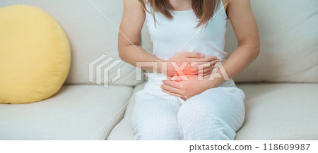 woman having abdomen ache due to Stomach pain, digestion with constipation or Diarrhea from food poisoning, female problem and Endometriosis, Hysterectomy, Stomachache and Menstrual on sofa at home 118609987